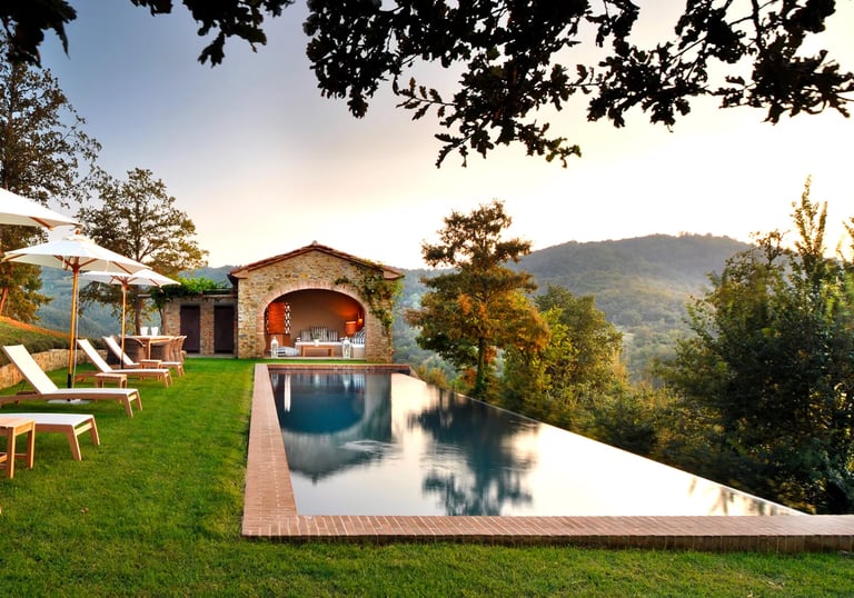 Infinity-edge pool with deep blue water and natural stone coping blending into the surrounding hills