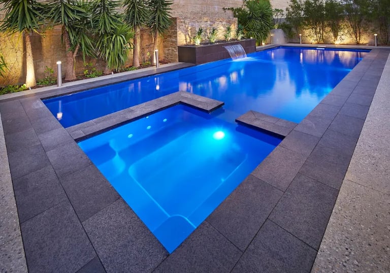  Modern rectangular pool with vivid blue LED-lit water and dark grey tiling plus raised square spa.