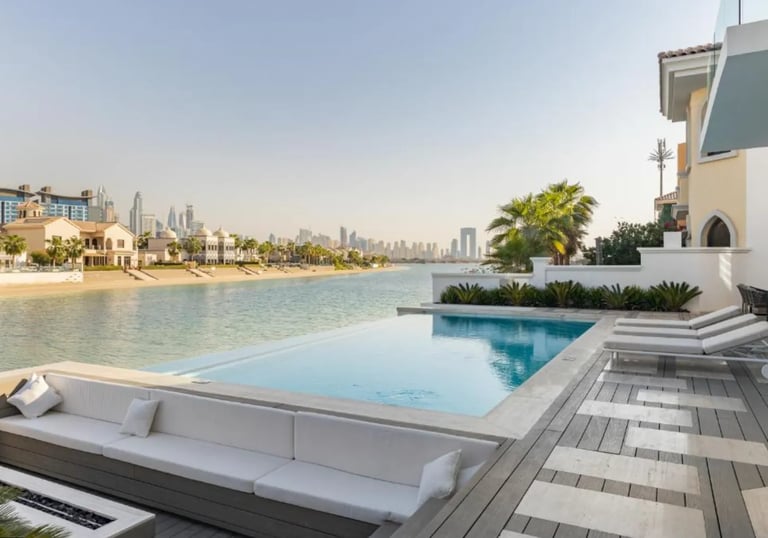 Modern infinity-edge pool with pale blue water and light stone tiles overlooking waterfront skyline