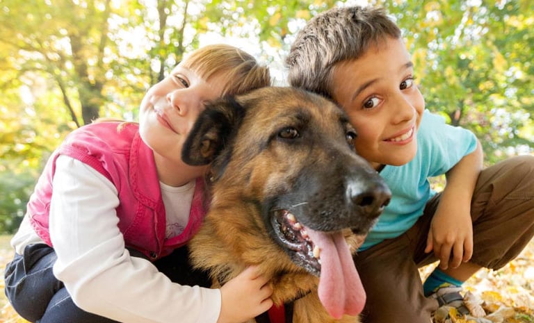 duas crianças posando com um cachorro grande