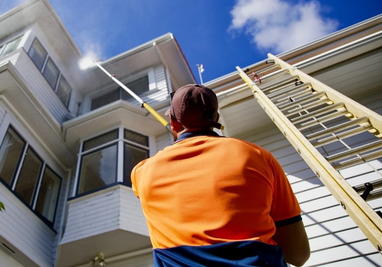 a man standing in front of a house using house soft wash technic