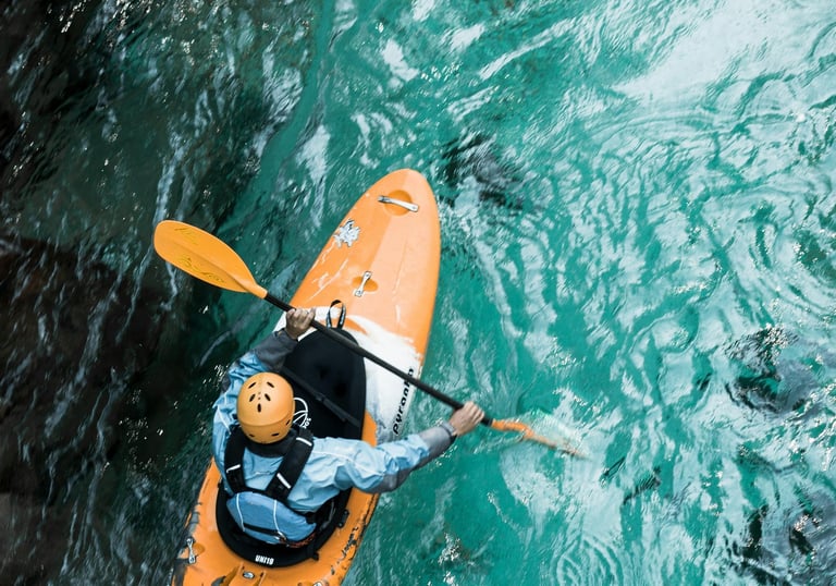 an adventurous person in a kayak in teal blue water