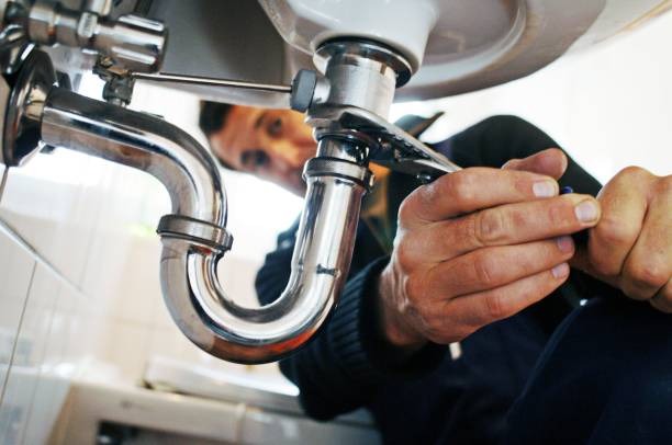 man turning a pipe under a sink with a special tool