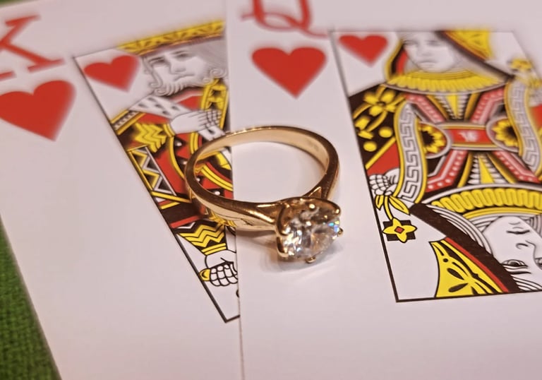 an engagement ring atop of the king and queen of hearts