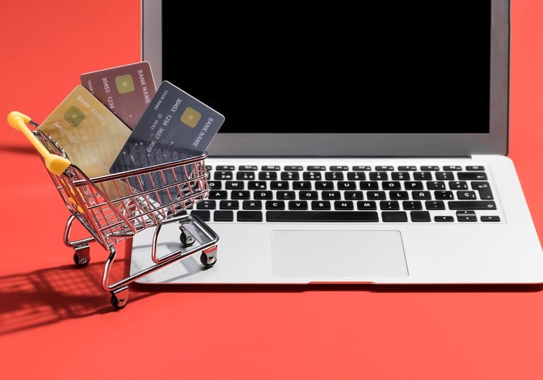 Mini chariot avec des cartes bancaires devant un ordinateur portable.