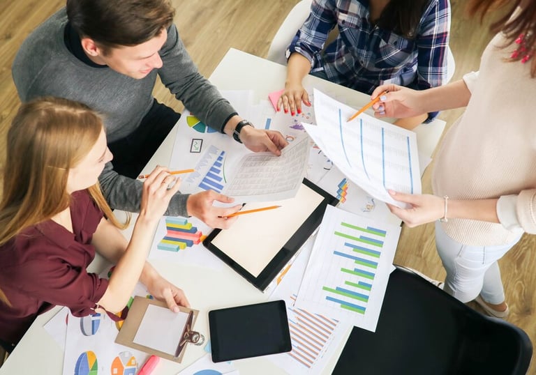 Groupe de personnes discutant de graphiques et de documents lors d'une réunion.