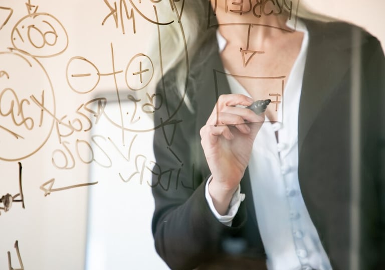 Personne écrivant des formules sur une vitre transparente.