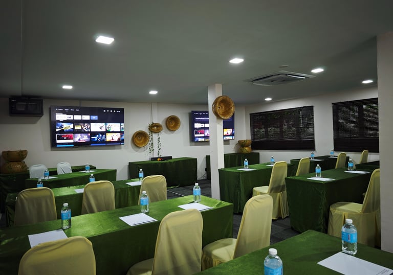 a room with green tables and chairs and a television