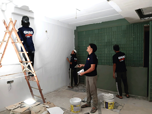 Professional house painters from Ghar Painting applying white and green paint to interior walls.