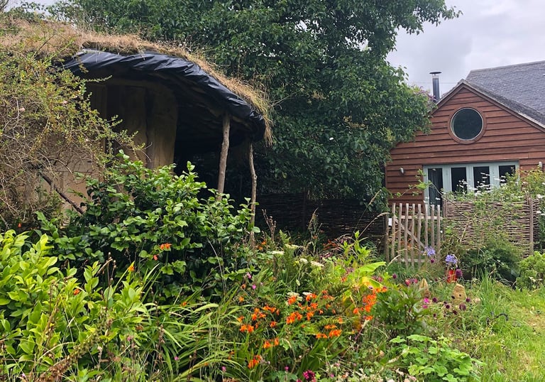 beautiful wild garden with a cob round-house and a wooden built house