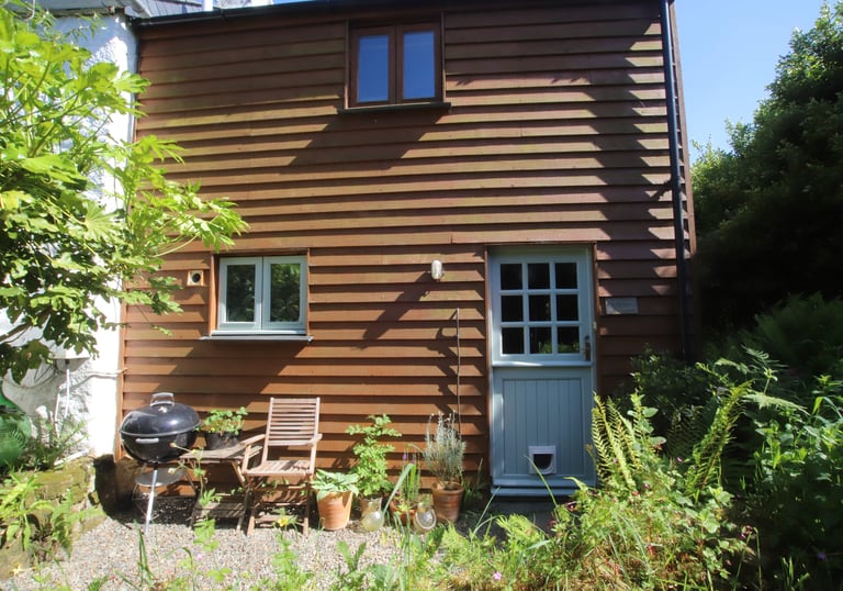 Holiday rental exterior front courtyard with chair and BBQ