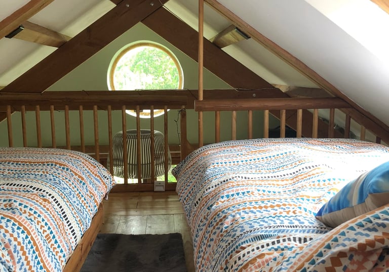 Holiday rental interior showing mezzanine twin beds overlooking circular window
