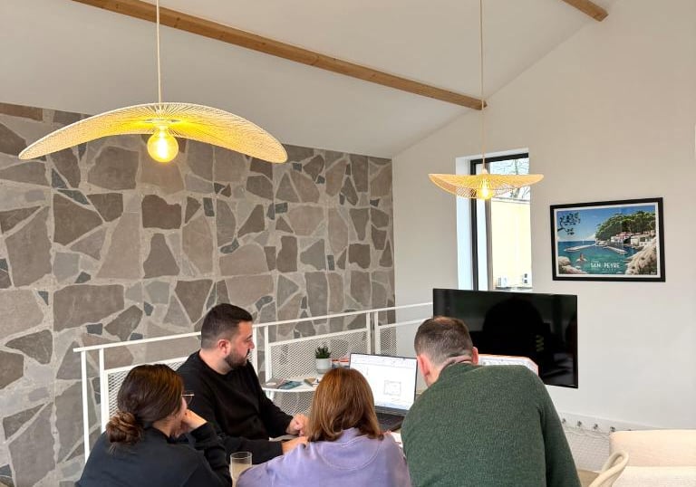 A diverse team collaborating in a modern office with stone walls and stylish pendant lighting.