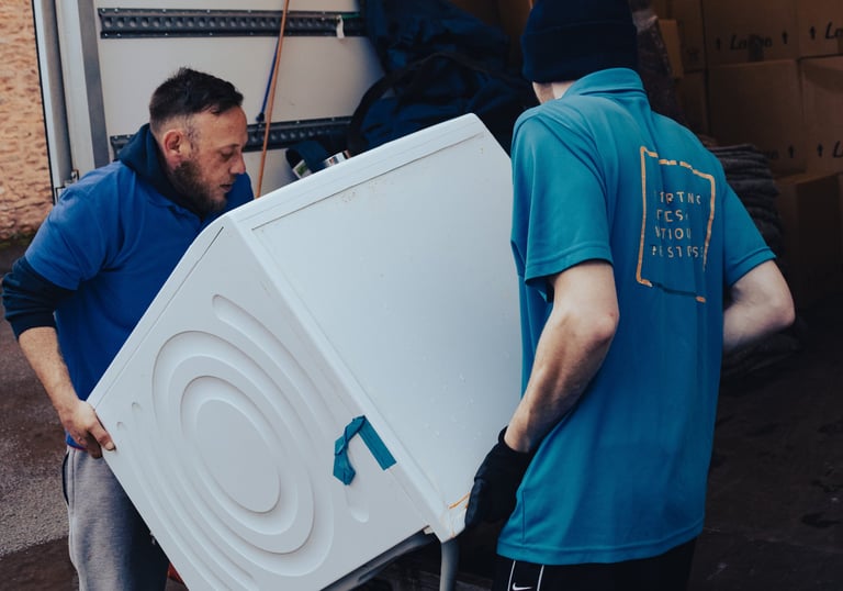 a man in a blue shirt is moving a refrigerator
