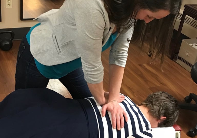 Chiropractor adjusting patient’s mid back showing a spinal manipulation.