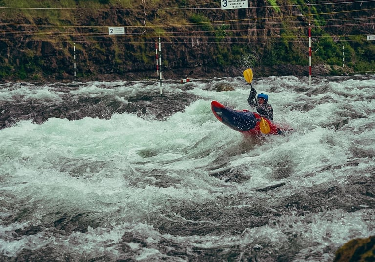 Woman kayaking down a rapid in a river through slalom gates during a race.