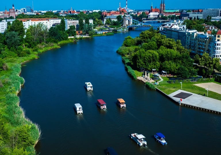 Aerial view of boats cruising the Oder River in Wroclaw, Poland with the city skyline and historic bridges.