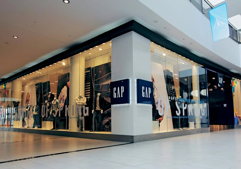 Drabužių parduotuvės vitrina prekybos centre su manekenais ir džinsais.