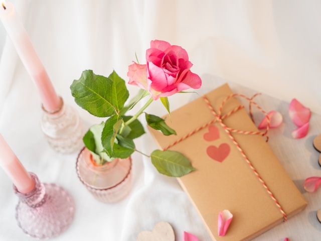Pink rose in a vase next to a wrapped present