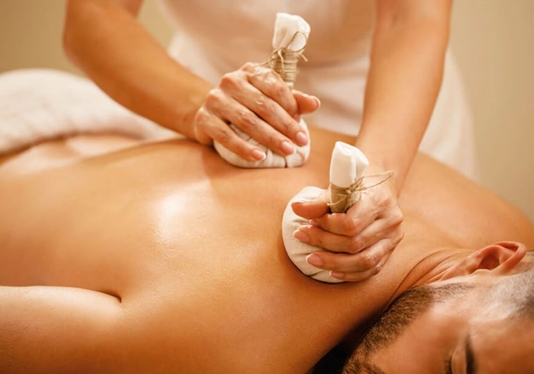 A man getting thai herbal compresses pressed into his back during a massage.