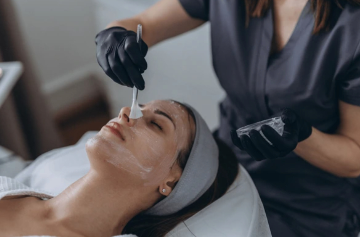 Woman getting a chemical mask brushed onto her face.