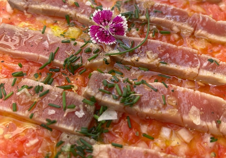 Plato de bigote de atún del Bar Las Tinajas Huelva, presentado con una flor decorativa encima.