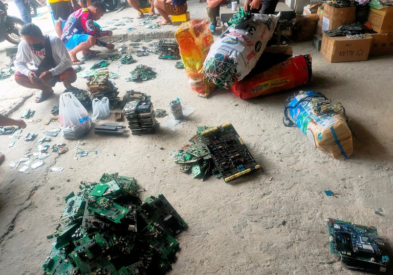 a group of people standing around a pile of broken electronics