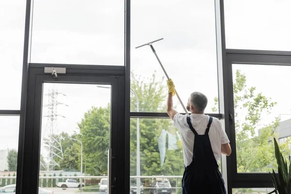 a man cleaning a window with a broom and a broom