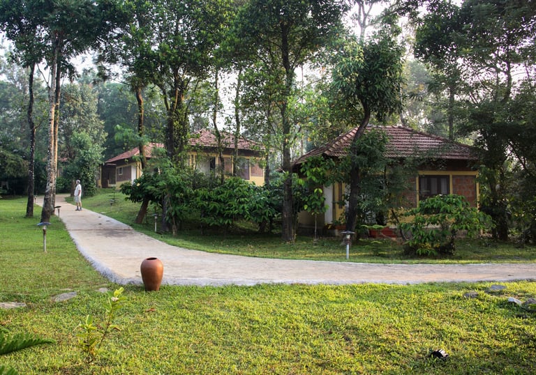 Natural cottages at Agraharam with a lush green pathway.