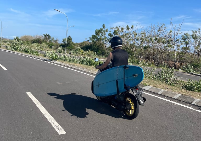 a man riding a scooter with a surfboard