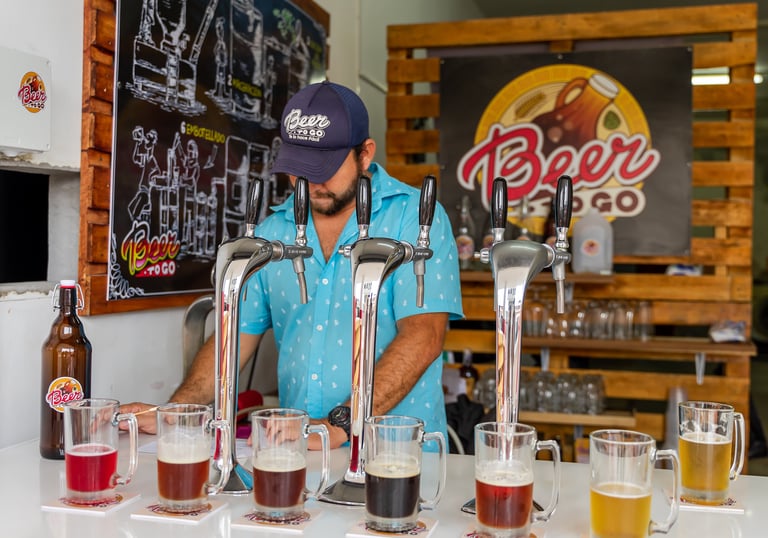 Un bartender en una barra con vasos de distintas cervezas artesanales