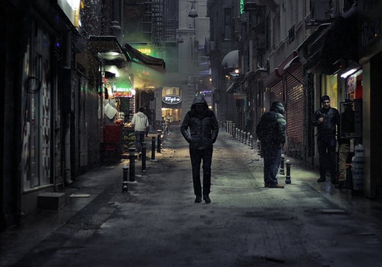 Person in a coat walking through an alley at night, evoking solitude and introspection