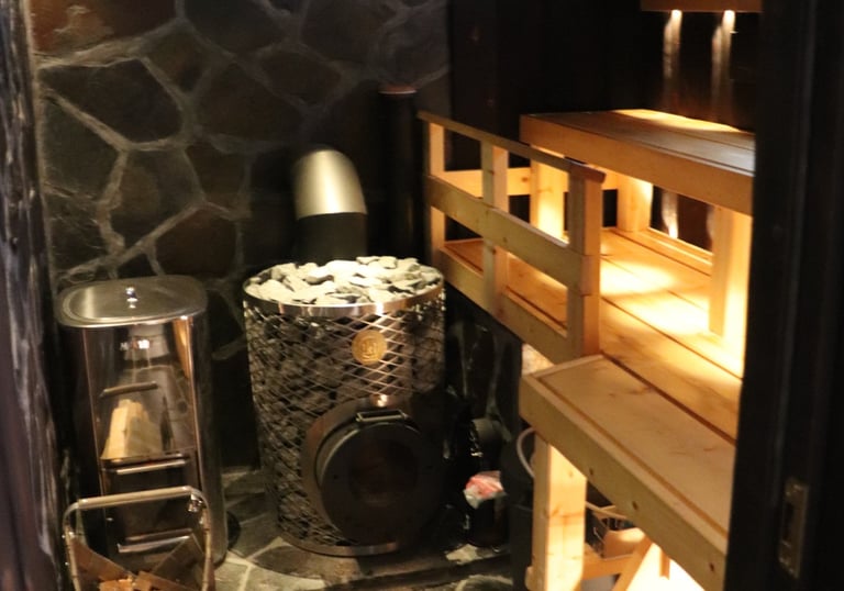 rustic sauna with iki kiuas and slate rockwork, burnt panels and dim lighting