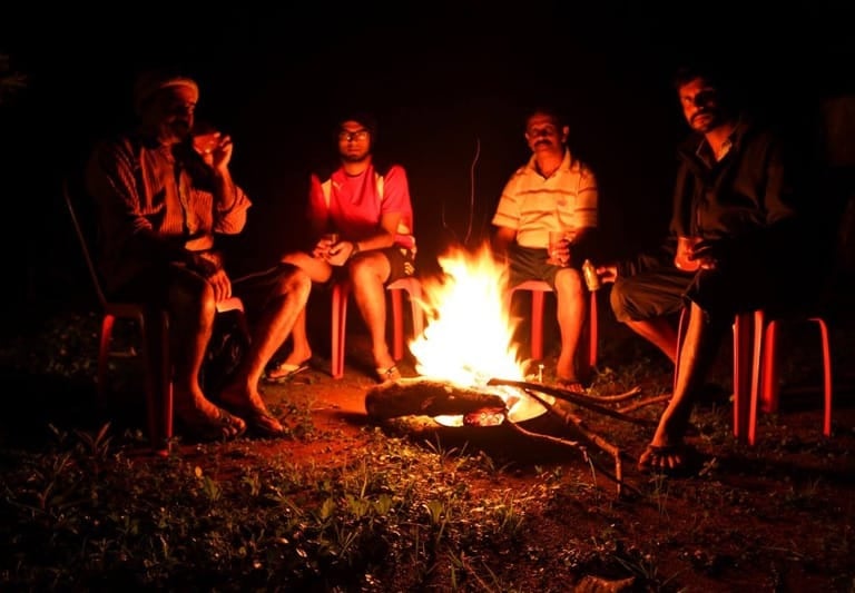 a group of people sitting around a campfire in Kattegadde Homestay - chikmagalur