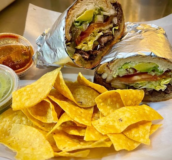 a Torta sandwich with chips and salsa on a plate