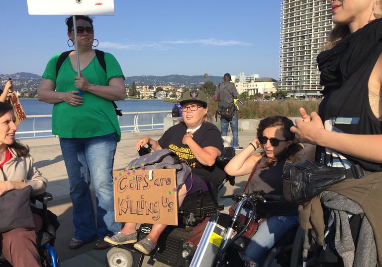 Photo of Stacey with friends at a protest with a sign saying "cops are killing us"