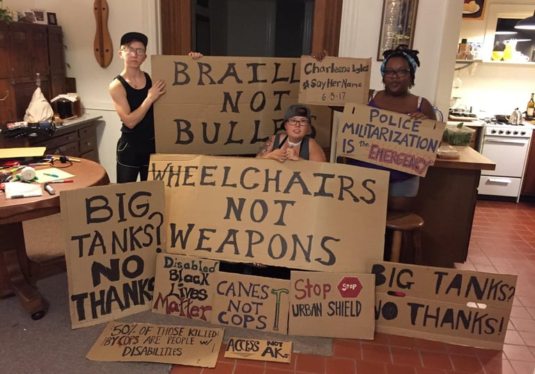 Photo of Stacey with Friends displaying posters they made in protest of Urban Shield and supporting BLM.