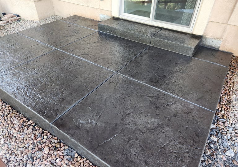 a colored and stamped concrete patio and a step with old granite texture stamp.