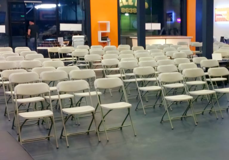 Sillas blancas plegables para eventos corporativos en el paso