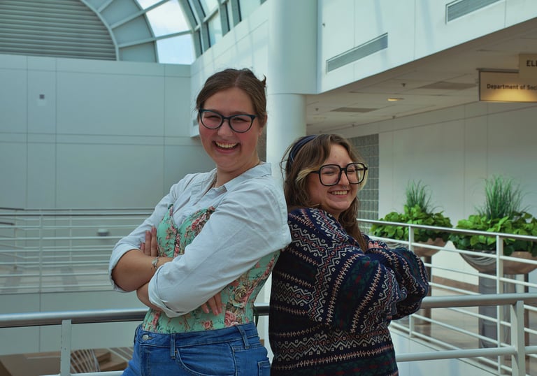 Two young college women best friends smiling and laughing in the camera.