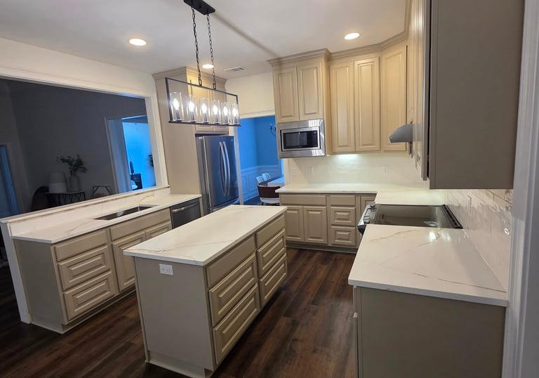Modern kitchen with beige cabinetry, white quartz countertops, and dark wood flooring.