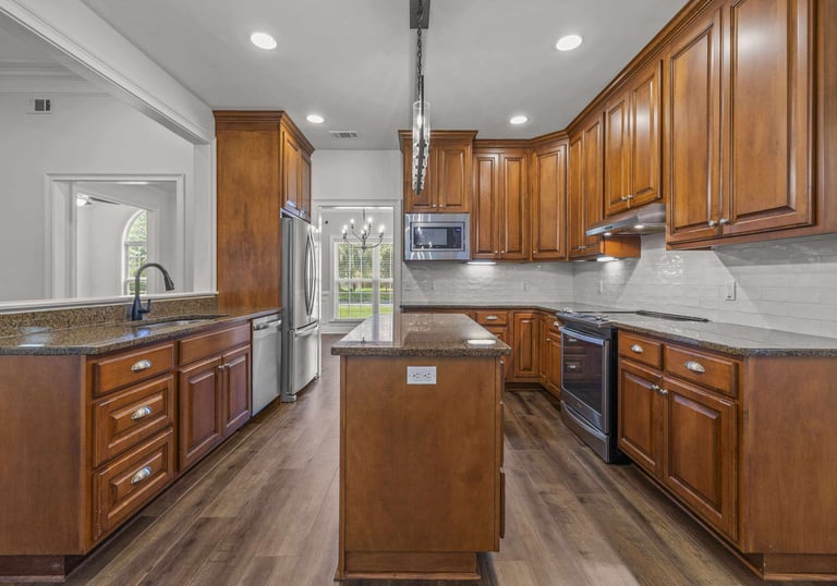 Modern kitchen with cherry wood cabinets, granite countertops, and stainless steel appliances.