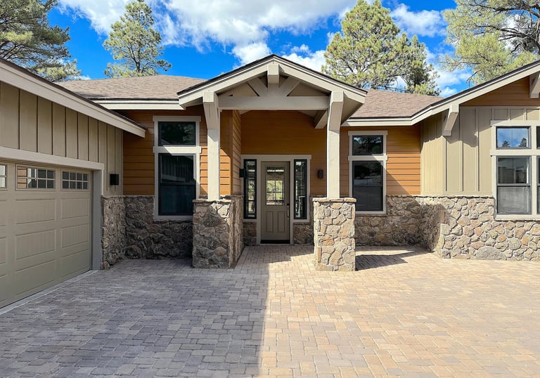 custom home with wood paneling, a driveway and large garage
