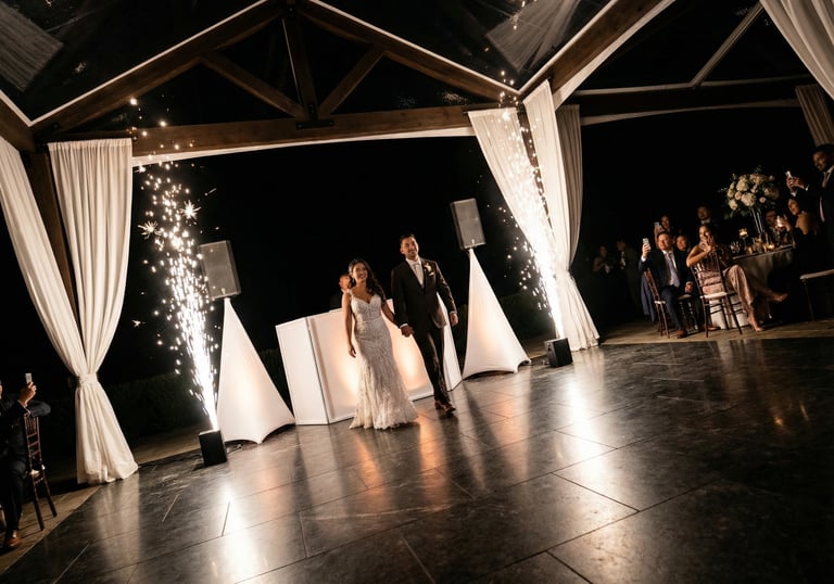 Bride and groom entering their outdoor wedding reception with cold sparkler fountains.