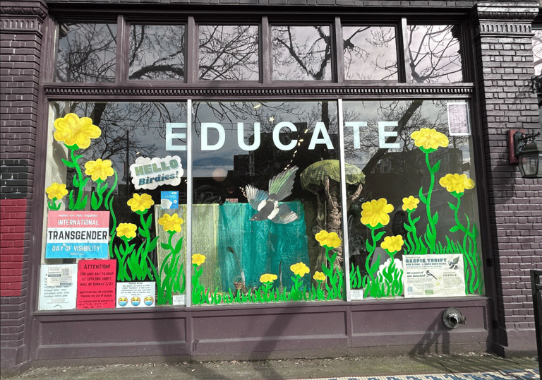 Large storefront window with the word EDUCATE printed on top of large painted yellow flowers