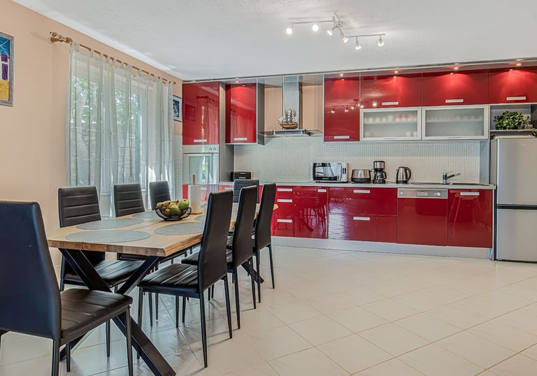 Spacious modern red kitchen with a large dining table for 8 at Villa Nika in Škrip, island of Brač
