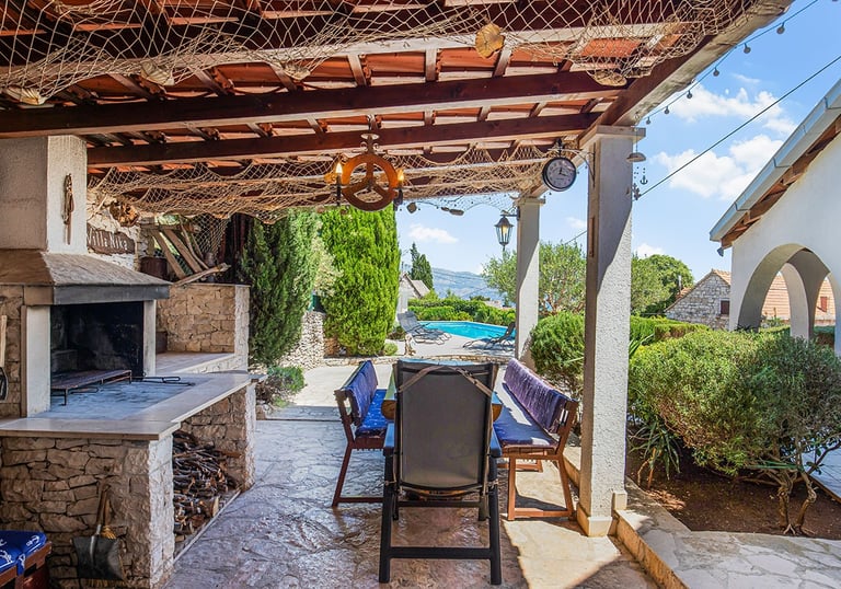 Villa Nika outdoor kitchen with wood-fired BBQ and pool view – Brač island