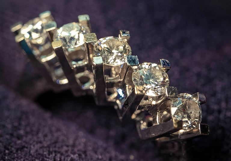 Close-up of diamond wedding rings on a dark fabric background, captured by Fred Art Studio.