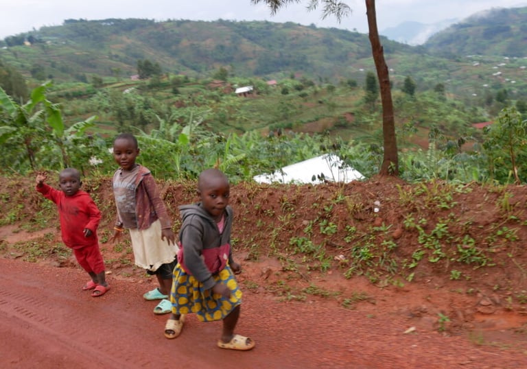 three children standing on a dirt road in their community