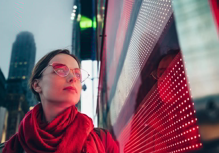 a woman in a red scarf and glasses next to led screen